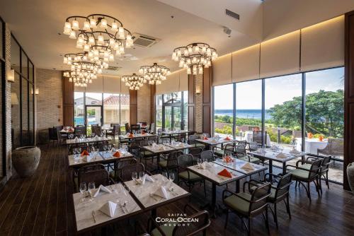 塞班Coral Ocean Resort的餐厅设有桌椅和吊灯。