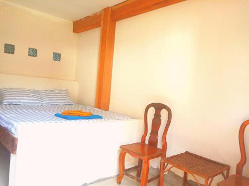 高龙撒冷岛懒人旅舍的一间卧室配有一张床和两张木椅