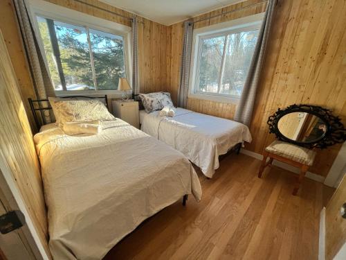 罗登Ski Mont Calm Water Falls River Rawdon Route 125的一间卧室配有两张床、椅子和两个窗户。