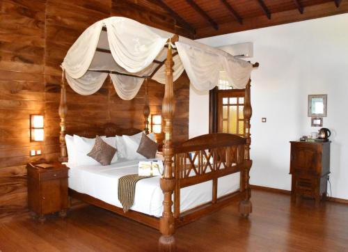 尼拉瓦利Nilaveli Beach Resort - Level 1 Certified的一间卧室设有天蓬床和木墙