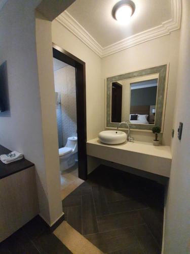 危地马拉L'Aurora Inn的一间带水槽、镜子和卫生间的浴室
