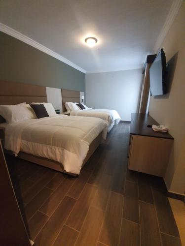 危地马拉L'Aurora Inn的酒店客房设有两张床和一台平面电视。
