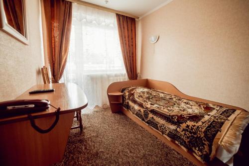 文尼察ПОДІЛЛЯ的一间卧室配有一张床、一张书桌和一个窗户。