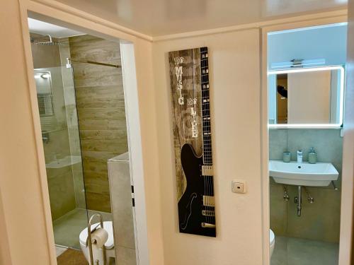 汉诺威Big Und Nice 3 Bedrooms的浴室位于墙上,设有吉他,毗邻水槽