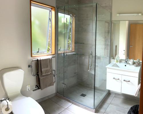 霍基蒂卡Jade Court Motel的一间带玻璃淋浴和水槽的浴室