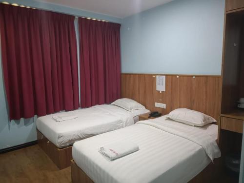 维多利亚AMBASSADOR LABUAN VIEW HOTEL的酒店客房设有两张床和红色窗帘
