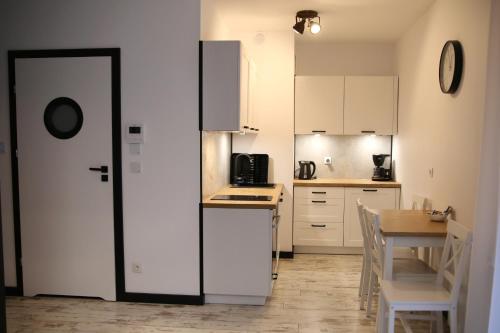 格但斯克P&K Motlawa Apartment的厨房配有白色橱柜和桌椅