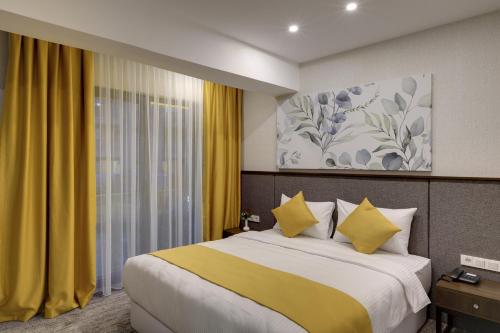 伯萨Leo Suites的一间卧室配有一张带黄色窗帘的大床