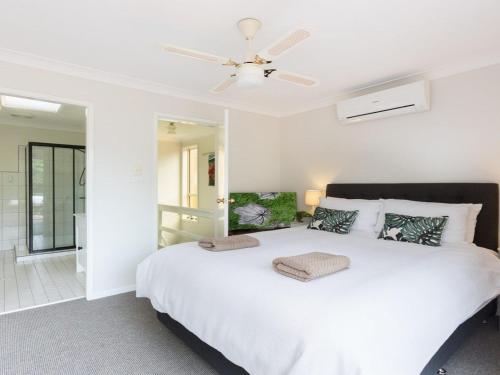 凯阿玛Tehidy Townhouse的卧室配有白色的床和吊扇