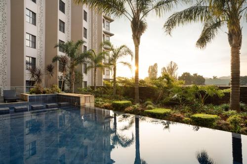 肯普顿帕克坦博OR尚品酒店的一座棕榈树游泳池和一座建筑