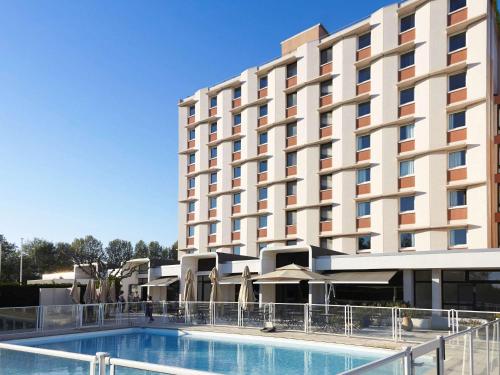 阿尔勒ibis Styles Arles Palais des Congrès的大楼前设有游泳池的酒店