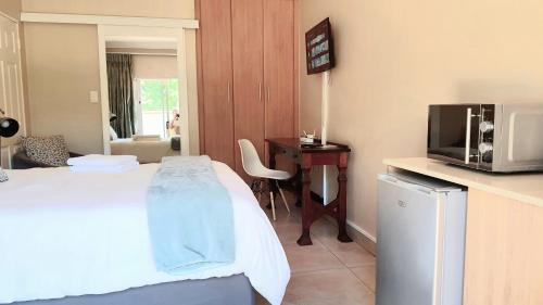 比勒陀利亚Langa's Gabedi Goshen的酒店的客房 - 带一张床、一台电视和一张书桌