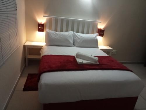 BizanaEmampingeni lodge的卧室配有一张大白色床和红色毯子