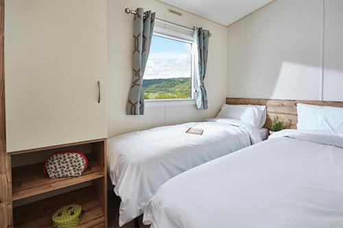 比特克 Moffat Manor Holiday Park的一间卧室设有两张床和窗户。