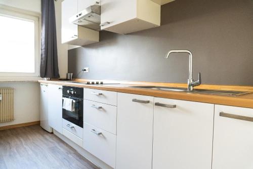 梅拉诺Flow Apartments Piave的厨房配有白色橱柜和水槽