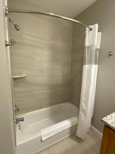 绍斯波特River Hotel of Southport的带淋浴的浴室配有白色浴缸。