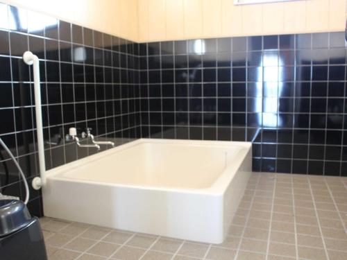 德之岛Yugaku Resort Kimukura - Vacation STAY 89356v的浴室设有浴缸,铺有黑色瓷砖。