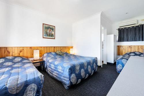 塔姆沃思Tamworth Budget Motel的酒店客房设有两张床和一张桌子。