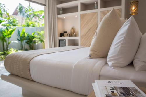 波普托Cielo Boutique Hotel & Spa Samui的一张带枕头的白色床和一张桌子上的书
