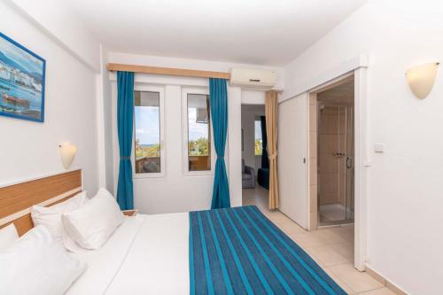 阿萨拉尔Armas Green Fugla Beach的一间卧室配有一张带蓝色窗帘的床和一扇窗户