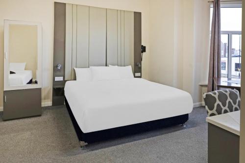 米德尔斯伯勒OYO The Baltimore Hotel的卧室配有一张白色大床和镜子