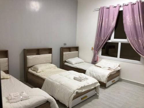Sa‘ab Banī KhamīsSab Bani Khamis House的一间卧室设有三张床和窗户。