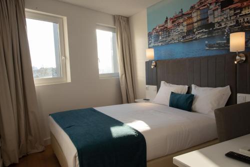 波尔图Hotel Porto Interface Trindade By Kavia的酒店客房设有一张床、一张书桌和窗户。