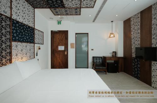 台南掘旅青年旅舍的卧室配有一张白色大床和一张书桌