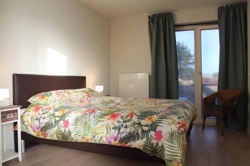 德帕内De Panne - Adinkerke - 't Voetbrugsje comfortabele nieuwbouw的一间卧室配有一张带彩色床罩和窗户的床。