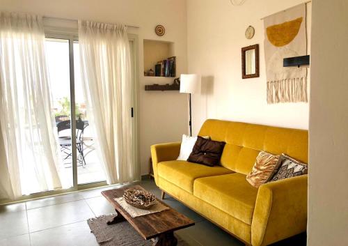 耶鲁姆יעלת חן Ya'alat hen的客厅配有黄色的沙发和桌子