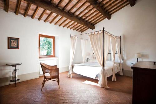 San Lorenzo Nuovo拉斯皮内塔度假屋的一间卧室配有一张天蓬床和一把椅子