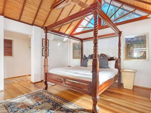 拜伦湾Amala Villa的一张华盖床,位于一个铺有木地板的房间