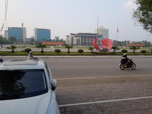 Bắc GiangKhách Sạn Hương Sơn的一辆白车,与骑摩托车的人一起沿着街道行驶