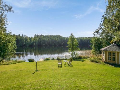 KosulaHoliday Home Ahvenranta by Interhome的一个带两把椅子的院子和湖边的房子