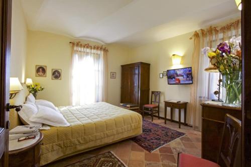 阿尔法诺纳塔Relais Castello di Razzano的一间卧室配有一张床、一张书桌和一个窗户。