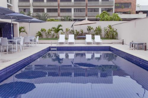 里约热内卢Americas Townhouse Hotel的游泳池配有椅子、桌子和遮阳伞