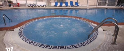 比韦罗塞壬海妖酒店的大楼内带蓝色椅子的大型游泳池