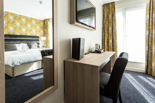诺丁汉The Residence Hotel at The Nottinghamshire Golf & Country Club的酒店客房配有一张床和一张书桌及一台电视