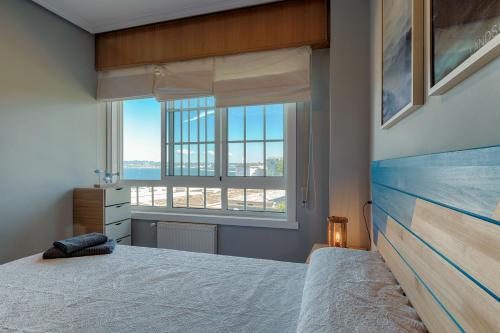 拉科鲁尼亚San Amaro Beach 3 by TheBlueWaveApartments com的一间卧室设有一张床和一个大窗户
