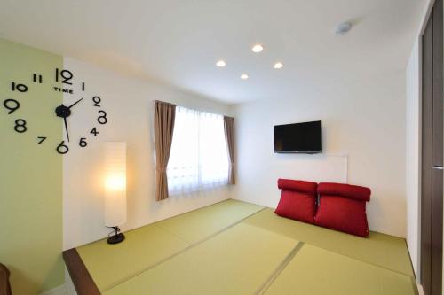 端岛Guest House Gifuhashima COCONE / Vacation STAY 33938的一间带时钟和两张红色椅子的客厅
