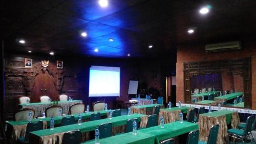 日惹Hotel Bifa Yogyakarta的配有绿色桌椅和屏幕的房间