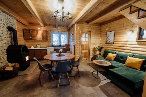 ZdówJurajskie Domki Pod Młyńską Skałą的客厅配有绿色沙发和桌子