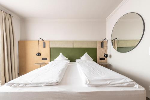 湖滨福煦Hotel Jakob的卧室配有一张带镜子的白色大床