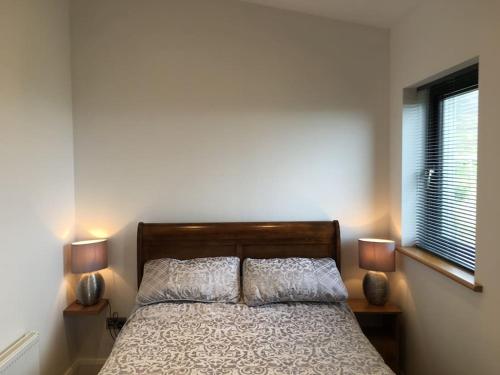 格伦科伦基尔Silver Strand Chalets的一间卧室配有一张带两盏灯的床和一扇窗户。