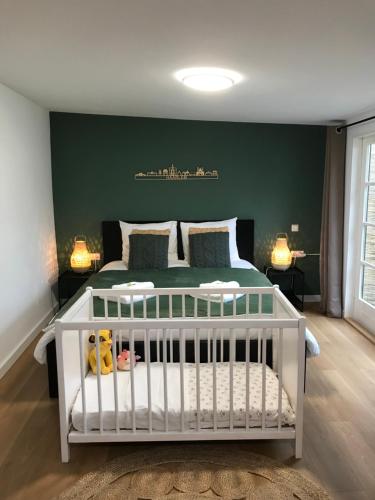 哈莱姆De Haarlemse Logeerkamer的卧室里设有一张白色的婴儿床,卧室里设有绿色的墙壁