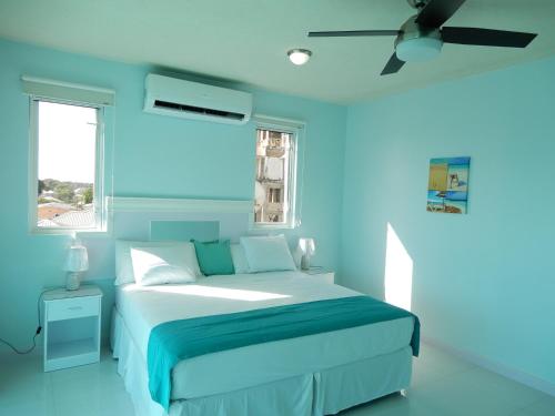 基督教堂市Oistins Bayview Apartments的蓝色卧室配有床和吊扇