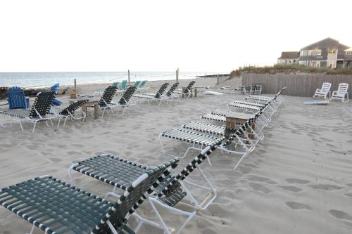 丹尼斯港By The Sea Guests Bed & Breakfast and Suites的海滩上一排躺椅和桌子