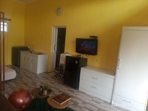 CigasongPondok Wammy Syariah的一间起居室,在黄色的墙上配有电视