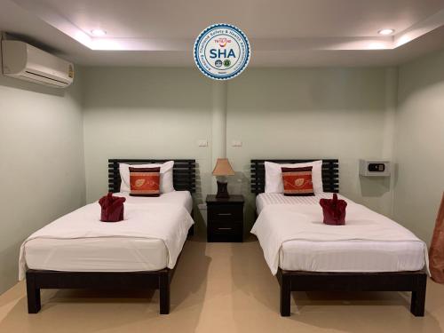 奈扬海滩Naiyang Seaview Place Resort的墙上有标牌的房间的两张床