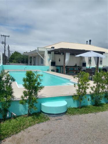 帕罗卡02 - CASA praia PINHEIRA pousada的房子前面的蓝色游泳池